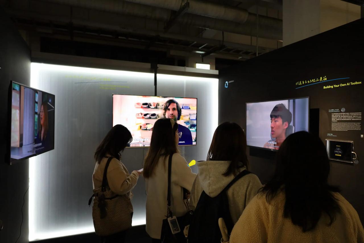 インタビュー動画のモニターの前に集まる人々