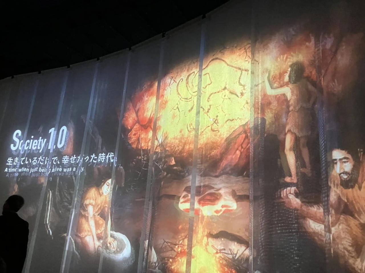 巨大ビジョンに、Society1.0の時代、洞窟で暮らす人々の様子が映し出されている