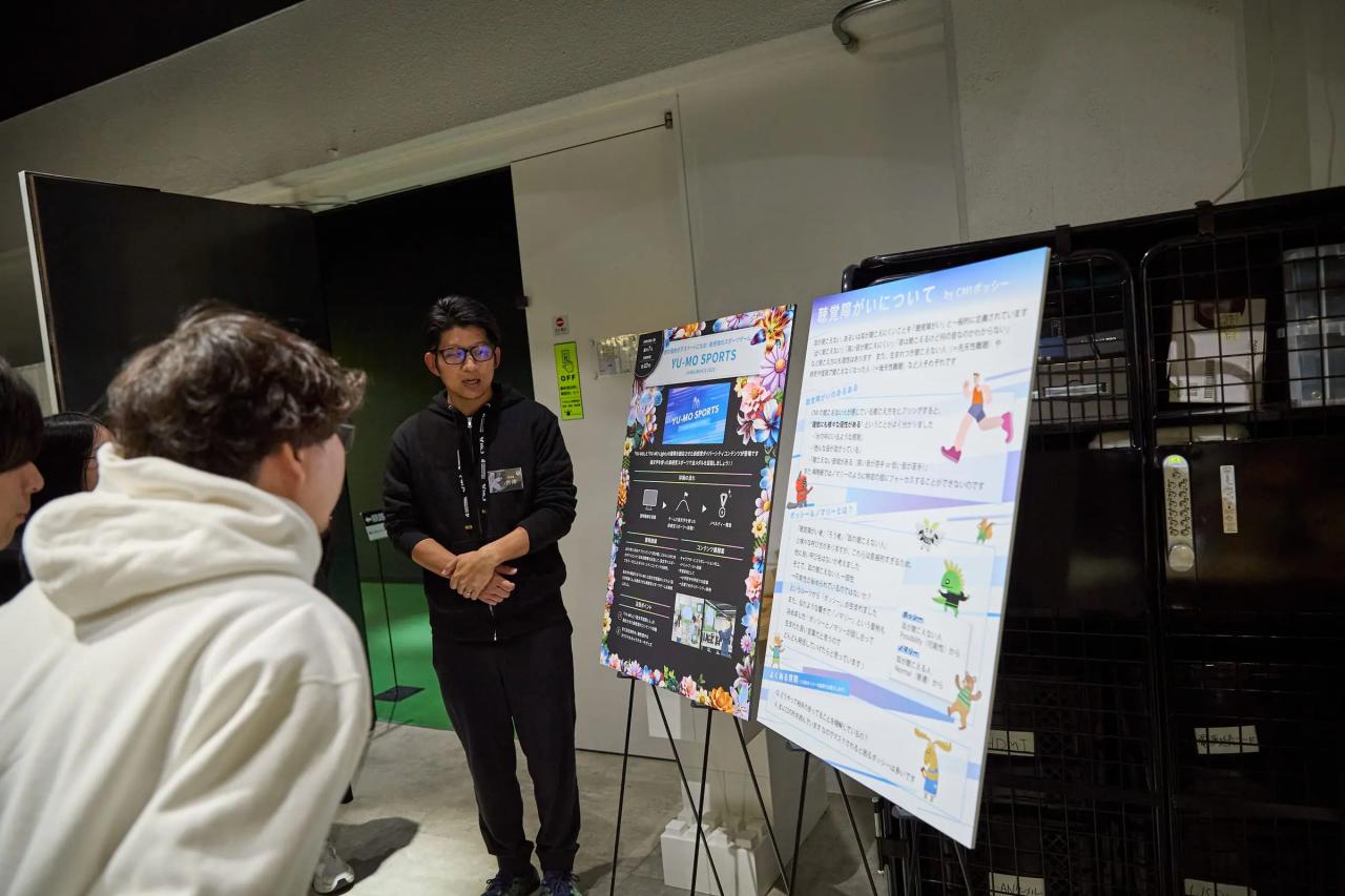 パネルの前でゲーム説明を行う丹青社社員